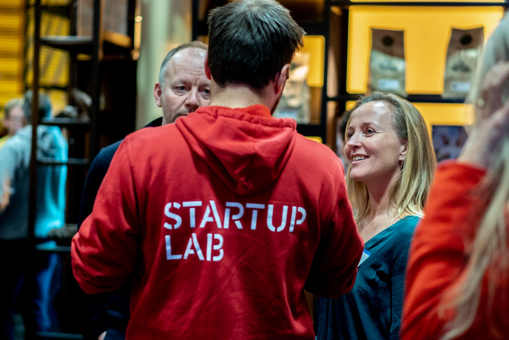 Mann med StartupLab-genser snakker med mann og kvinne.